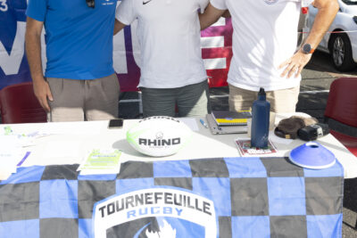 photo portrait du stand de Tournefeuille rugby avec trois hommes debout derrière qui se tiennent par les bras dans le dos et sourient à l'objectif - Agrandir l'image 7 sur 16, fenêtre modale