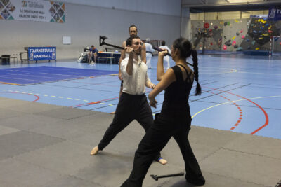 photo d'un jeune homme et d'une jeune femme habillés en noir et blanc, sur un tatami, qui se font face avec une hâche et une épée dans la main, simulant un combat - Agrandir l'image 8 sur 14, fenêtre modale