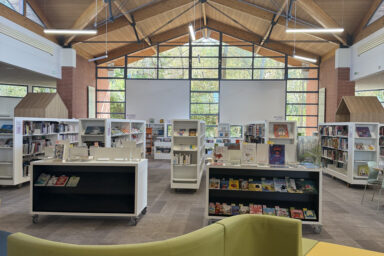 photo de l'intérieur de la Médiathèque avec mobilier de confort au premier plan et étagères blanches avec livres derrière