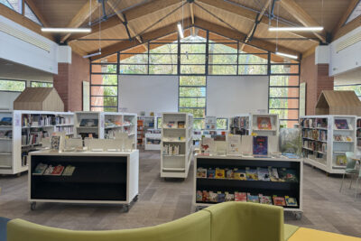 photo de l'intérieur de la Médiathèque avec mobilier de confort au premier plan et étagères blanches avec livres derrière - Agrandir l'image 3 sur 6, fenêtre modale