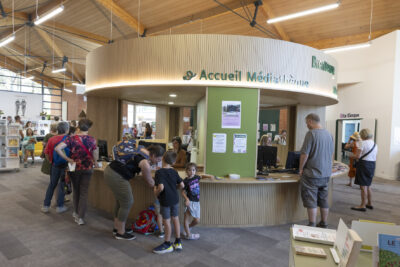 photo de l'entrée de la Médiathèque avec une borne d'accueil ronde, et des familles qui entrent - Agrandir l'image 4 sur 19, fenêtre modale