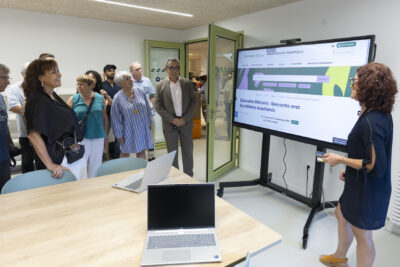 photo d'une pièce de conférence, avec sur la droite un grand écran sur lequel est projeté le site de la Médiathèque, sur la gauche, une dizaine de personnes regardent - Agrandir l'image 9 sur 19, fenêtre modale