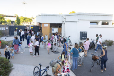 photo de familles devant l'école, il fait beau et le cadre est végétalisé
