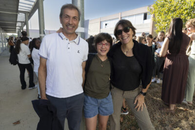 photo d'un couple d'une femme et d'un homme qui entourent un jeune collégien dans la cour du collège - Agrandir l'image 20 sur 25, fenêtre modale