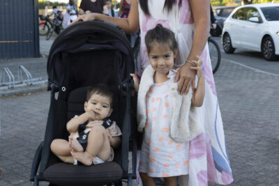 photo d'une femme avec une petite fille et un bébé dans sa poussette devant l'école, qui posent pour la photo - Agrandir l'image 6 sur 25, fenêtre modale