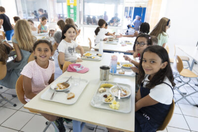 photo d'une table de cantine avec des enfants qui sourient à l'objectif - Agrandir l'image 14 sur 25, fenêtre modale