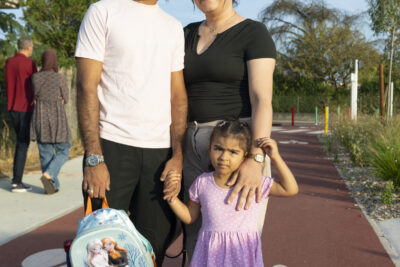 photo d'une famille, un homme et une femme et une petite fille qui sourient à l'objectif et posent sur une piste cyclable rouge - Agrandir l'image 24 sur 25, fenêtre modale