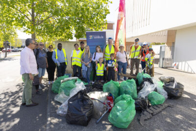 photo d'une quinzaine de personnes rassemblées avec quelques enfants, derrière un tas de sacs poubelles plein de déchets - Agrandir l'image 6 sur 9, fenêtre modale