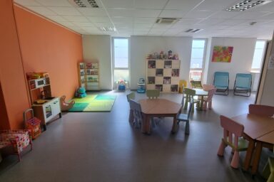 Photo de l'espace familles avec une grande pièce équipée de tables et jeux pour enfants