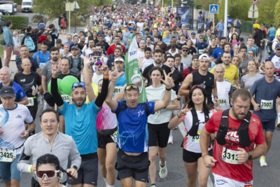 photo de milliers de coureurs sur la route, au premier plan deux hommes ont les bras en l'air et sourient pour la photo, une femme fait le signe peace des deux mains - Agrandir l'image 5 sur 19, fenêtre modale