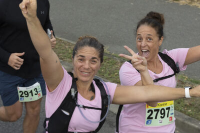 photo paysage de deux coureuses vêtues de rose qui sourient à l'objectif, une a les bras en l'air, l'autre fait le signe peace de la main droite - Agrandir l'image 8 sur 19, fenêtre modale