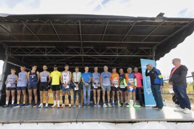 photo d'une quinzaine de coureurs rassemblés sur une scène, certains sont médaillés, ils tiennent une enveloppe dans les mains - Agrandir l'image 15 sur 19, fenêtre modale