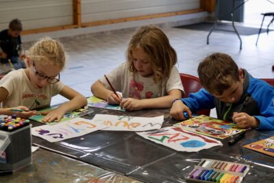 Photo de trois enfants assis à une table en train de dessiner sur des feuilles avec concentration - Agrandir l'image 14 sur 18, fenêtre modale