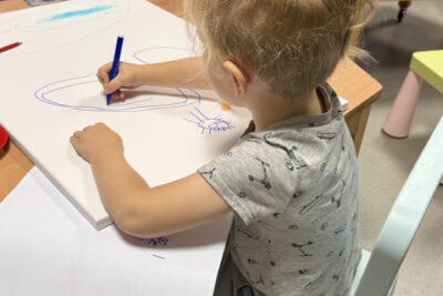 photo d'une jeune fille blonde en train de dessiner sur une grande feuille, sur une table - Agrandir l'image 5 sur 5, fenêtre modale