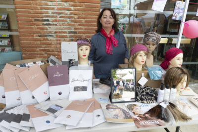 photo d'un stand de bonnets/foulards en extérieur, une femme derrière sourit à l'objectif - Agrandir l'image 6 sur 16, fenêtre modale