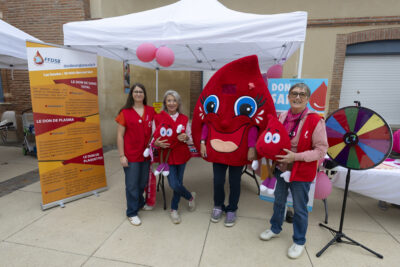 photo du stand du don du sang avec quatre personnes, dont trois femmes habillées d'un gilet rouge et une mascotte en forme de goutte de sang - Agrandir l'image 9 sur 16, fenêtre modale