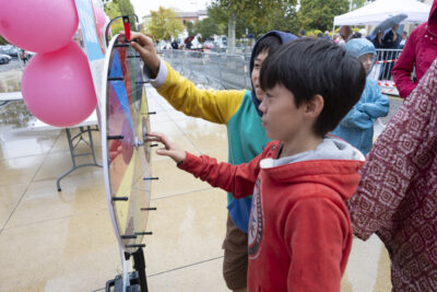 photo de deux enfants qui jouent à un jeu de roue à faire tourner, en extérieur, sous un temps pluvieux - Agrandir l'image 2 sur 16, fenêtre modale