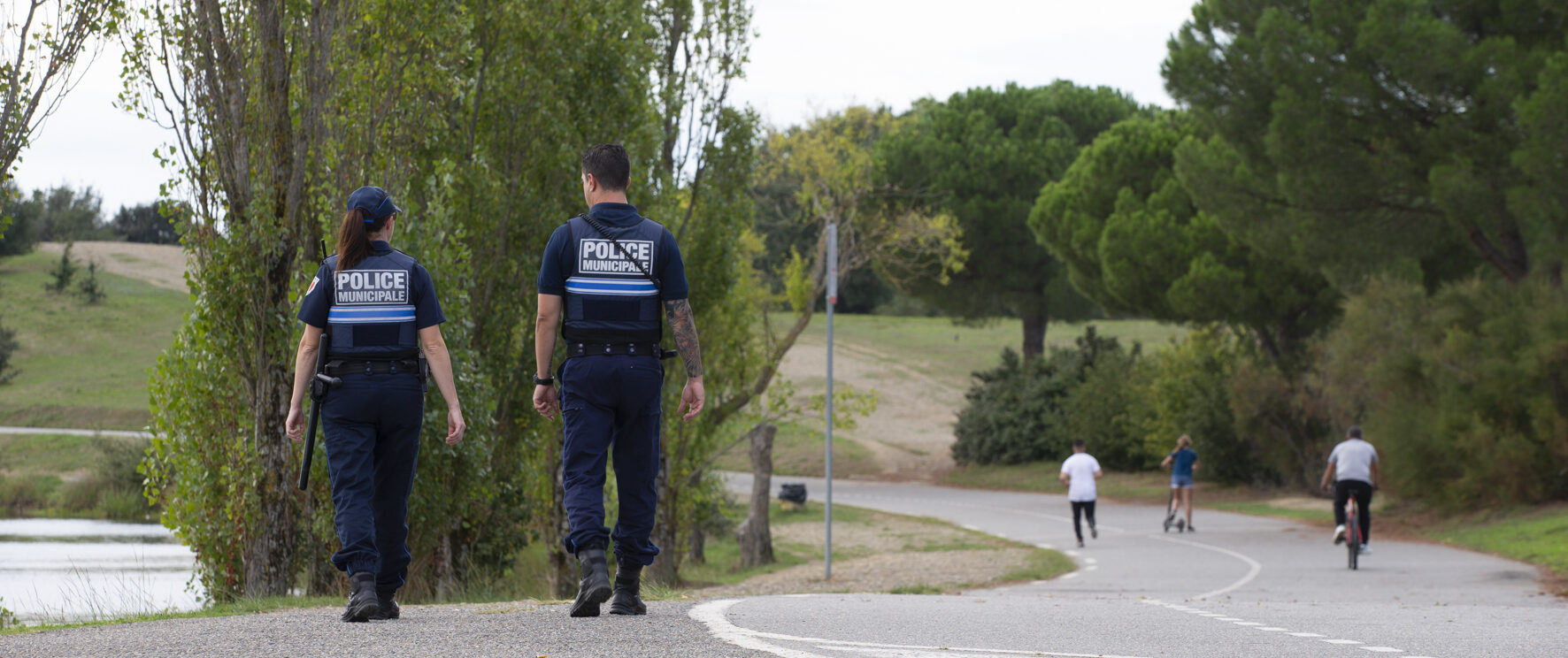 Deux policiers municipaux de dos marchent dans la rue