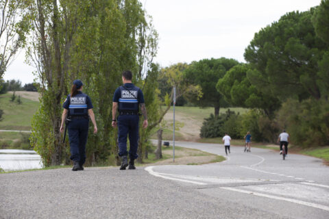 Deux policiers municipaux de dos marchent dans la rue