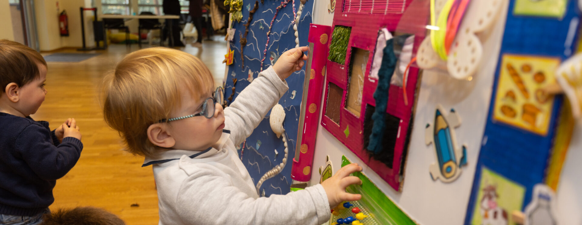Petits enfants qui regardent un panneau avec des dessins et autres créations