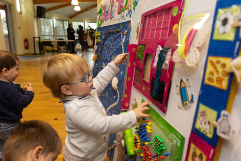 Petits enfants qui regardent un panneau avec des dessins et autres créations