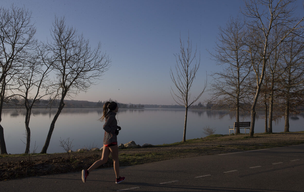 Joggeuse qui court à côté d'un lac au soleil couchant