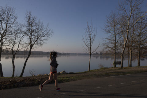 Joggeuse qui court à côté d'un lac au soleil couchant