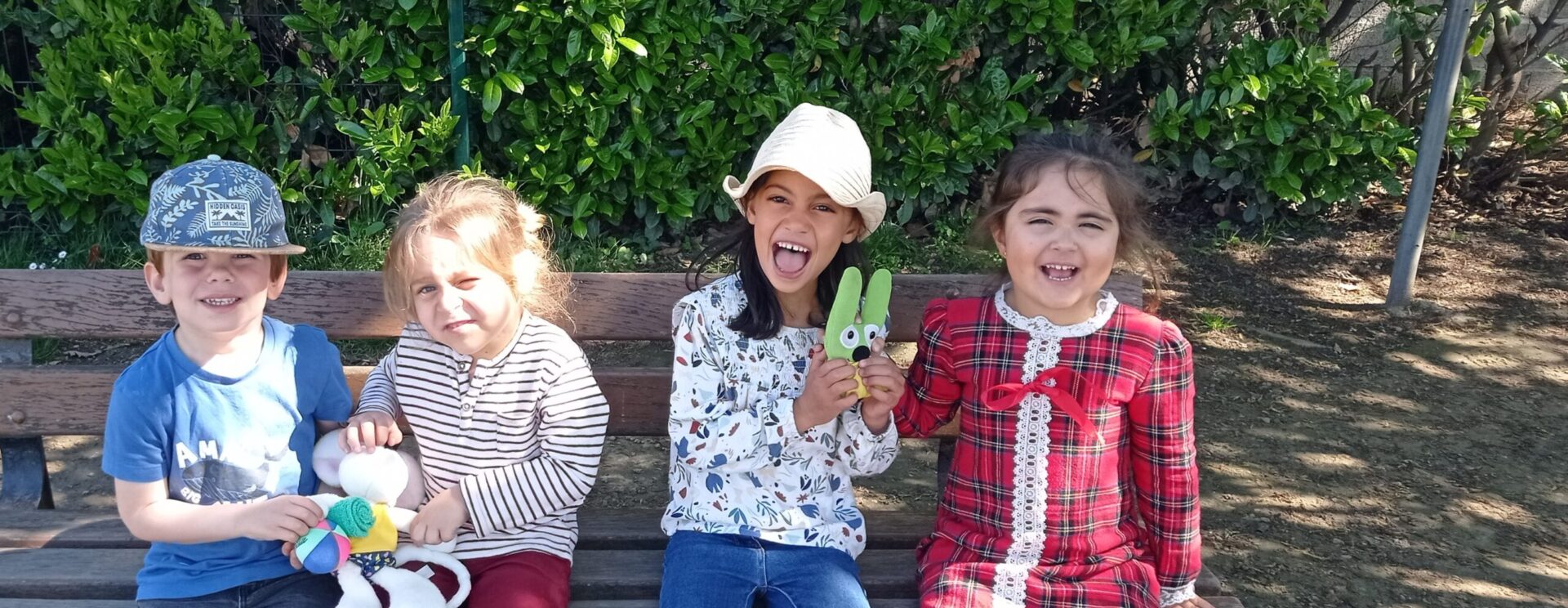 Quatre enfants sur un banc regardent l'objectif