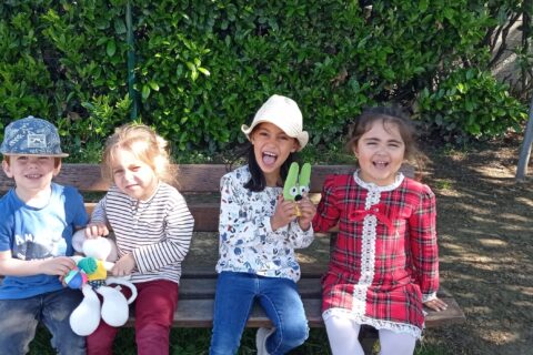 Quatre enfants sur un banc regardent l'objectif