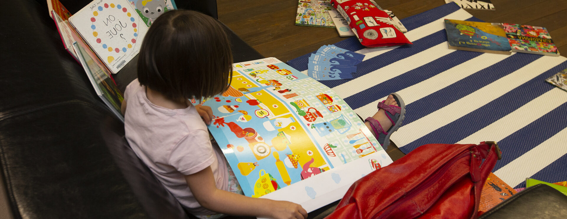 Enfant vu de dos qui lit un grand livre illustré