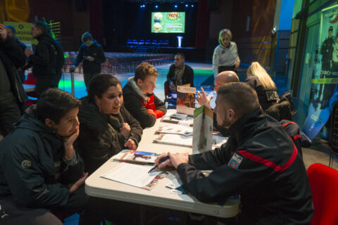 Jeunes accompagnés de parents qui discutent avec des adultes à un stand d'information