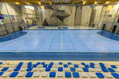 Photo du terrain de handball, vue de face depuis les gradins, avec dans le fond le mur d'escalade - Agrandir l'image 2 sur 3, fenêtre modale