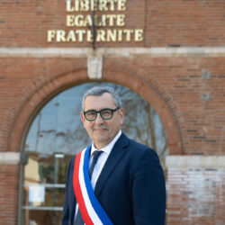 Photo du Maire Frédéric Parre devant le Mairie, portant l'écharpe tricolore