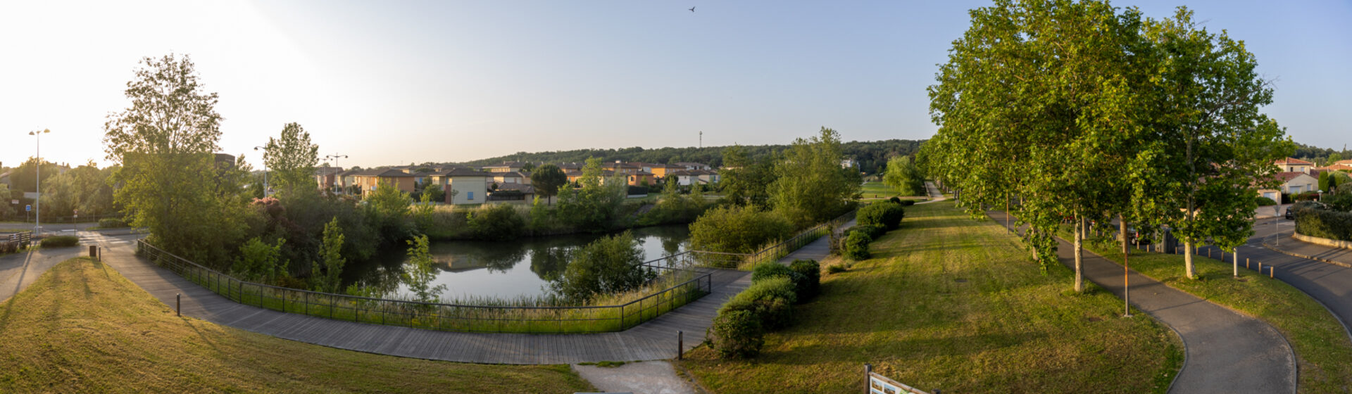 Photo panoramique d'un parc avec chemins piétons et petite étendue d'eau