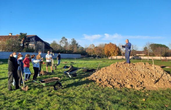 Photo de personnes rassemblées dans un espace vert avec brouettes et autres équipements