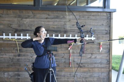 Photo d'une archère qui bande son arc, la photo est prise de profil - Agrandir l'image, fenêtre modale