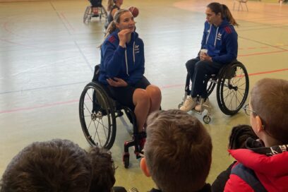 Photo de deux joueuses de basket fauteuil qui échangent avec des enfants au premier plan, vus de dos - Agrandir l'image, fenêtre modale