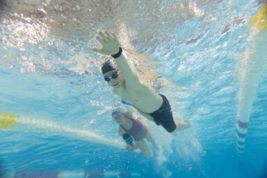 Photo de jeune nageur qui fait du crawl, prise en contreplongée dans l'eau de la piscine