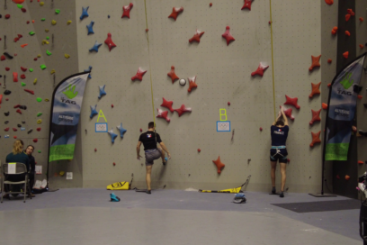 Deux grimpeurs portant un teeshirt noir sur lequel on voit le drapeau de l'équipe de France font face au mur d'escalade et s'apprêtent à grimper - Agrandir l'image, fenêtre modale