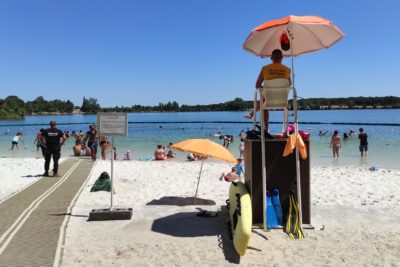 Photo de la Ramée plage, temps ensoleillé, on voit le sauveteur assis en hauteur sur sa chaise observer les baigneurs - Agrandir l'image 1 sur 3, fenêtre modale