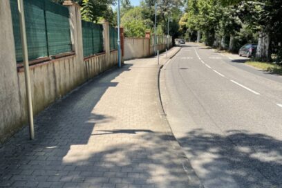 Photo d'une rue, sur la gauche des habitations, sur la droite des arbres - Agrandir l'image, fenêtre modale