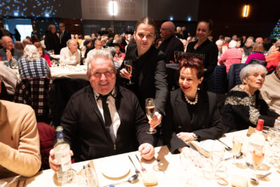 Photo d'une jeune femme qui sert une coupe de champagne à deux séniors à table, très bien habillés avec costume cravate - Agrandir l'image 10 sur 14, fenêtre modale