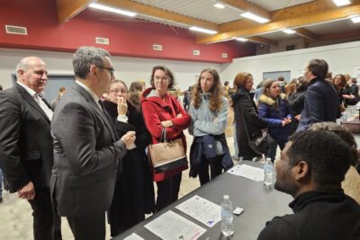 Le Maire Frédéric Parre échange avec des jeunes devant un stand d'information dans une salle avec de nombreux jeunes réunis autour de stands d'information - Agrandir l'image 1 sur 13, fenêtre modale