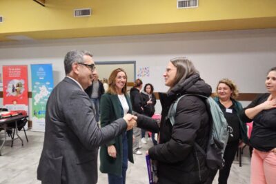 Le Maire Frédéric Parre serre la main d'une femme dans une salle, d'autres femmes les regardent en souriant - Agrandir l'image 4 sur 13, fenêtre modale