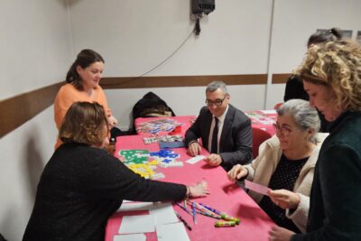 Le Maire et quatre femmes autour d'une table couverte d'une nappe rose, avec des documents colorés disposés dessus - Agrandir l'image 6 sur 13, fenêtre modale