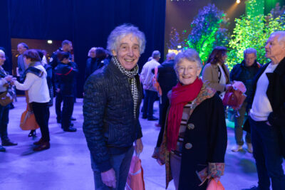 Photo d'un homme et d'une femme qui sourient à l'object. On voit derrière eux d'autres personne échanger entre elles - Agrandir l'image 6 sur 22, fenêtre modale
