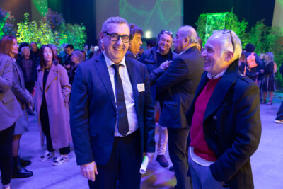 Photo du Maire Frédéric Parre qui échange avec un homme à la soirée des voeux, il y a du monde derrière lui, des groupes de personnes qui échangent dans une ambiance conviviale - Agrandir l'image 1 sur 22, fenêtre modale