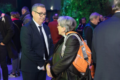 Photo du Maire Frédéric Parre qui salue une femme qui porte un sac à dos orange - Agrandir l'image 5 sur 22, fenêtre modale
