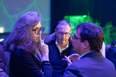 Deux personnes échangent entre elles, on voit un homme également à l'arrière plan entre elles - Agrandir l'image 22 sur 22, fenêtre modale