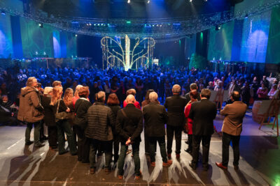 Photo des élus rassemblés de dos, avec la vue sur la salle et le monde réuni dans la salle avec une déco lumineuse et un éclairage bleu sombre - Agrandir l'image 2 sur 22, fenêtre modale